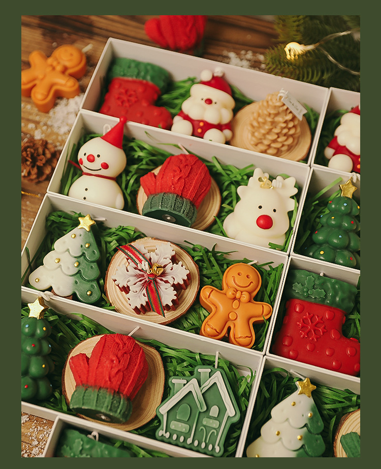 Gift box of shaped holiday candles packed over green raffia